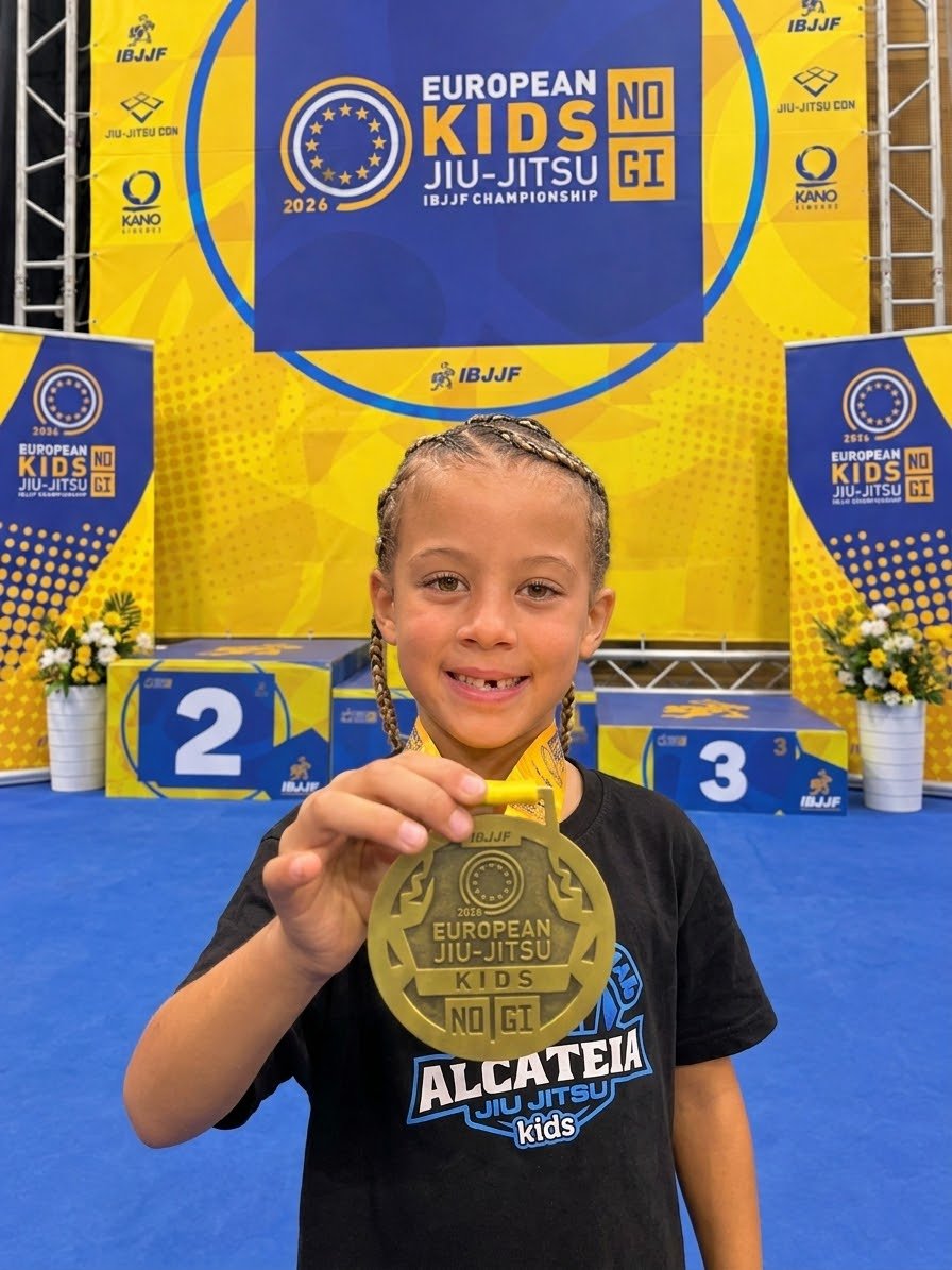 Aleyna holding her bronze medal in front of the podium at the European Kids No-Gi IBJJF Championship, Lisbon, October 2026.