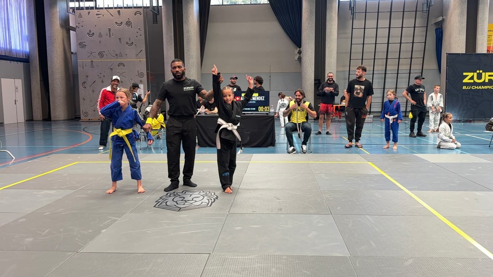 The referee raises Aleyna's arm after her Gi final win at the Züri Kids Cup BJJ Championship 2026.