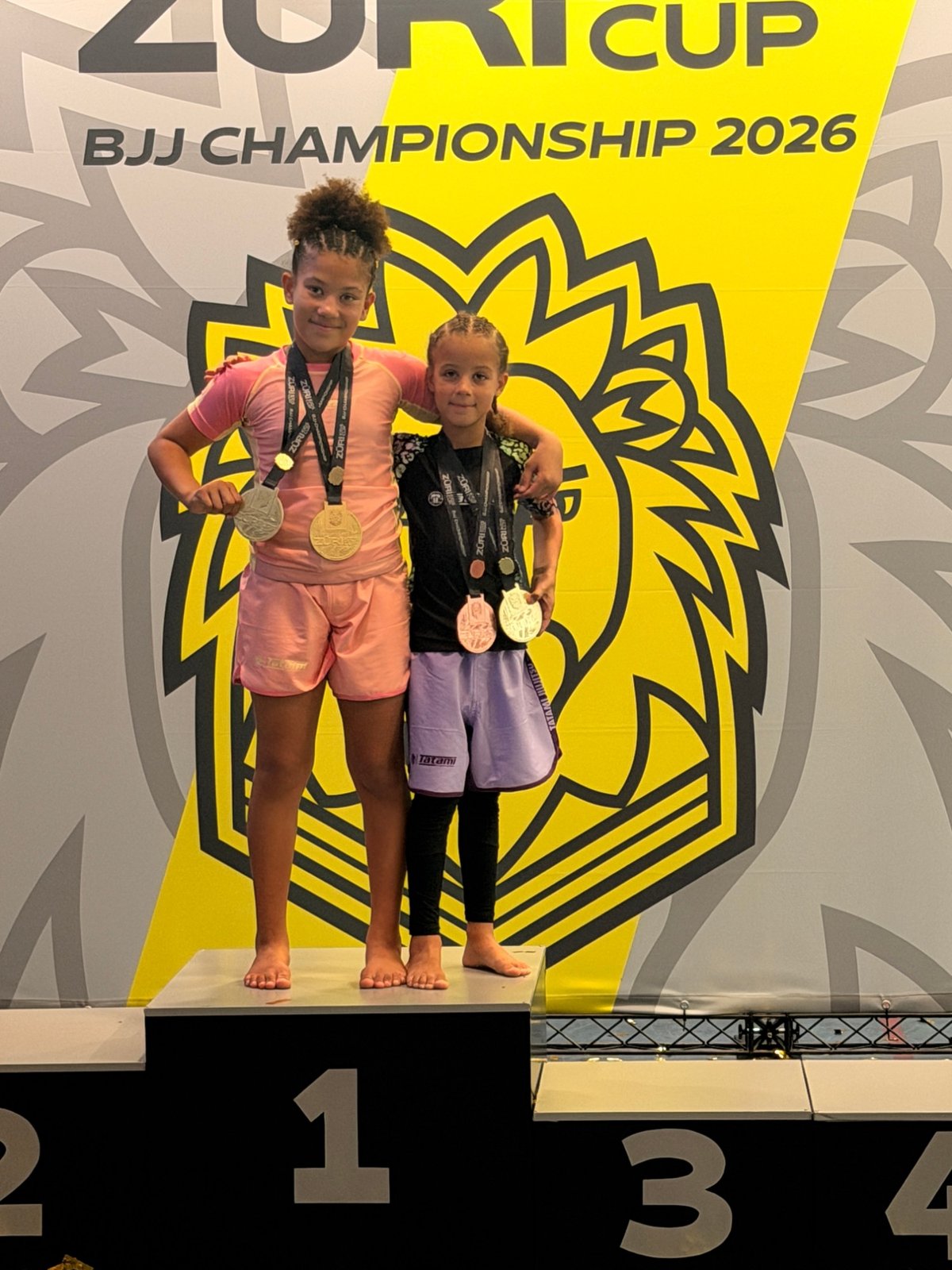 Aleyna and her sister together on the top step of the Züri Kids Cup BJJ Championship 2026 podium.