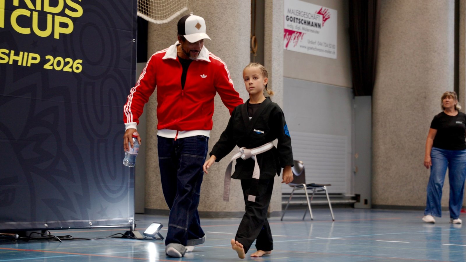 Aleyna walking onto the mat with her father before her Gi final at the Züri Kids Cup BJJ Championship 2026.
